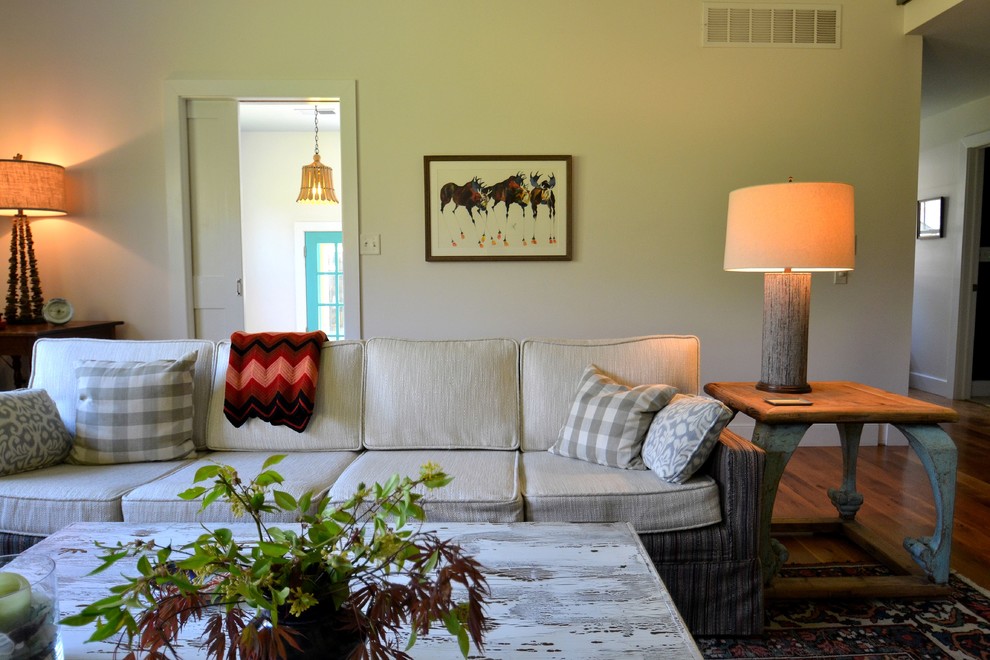 На фото: большая изолированная гостиная комната в стиле шебби-шик с белыми стенами, паркетным полом среднего тона, стандартным камином, фасадом камина из кирпича, телевизором на стене и коричневым полом