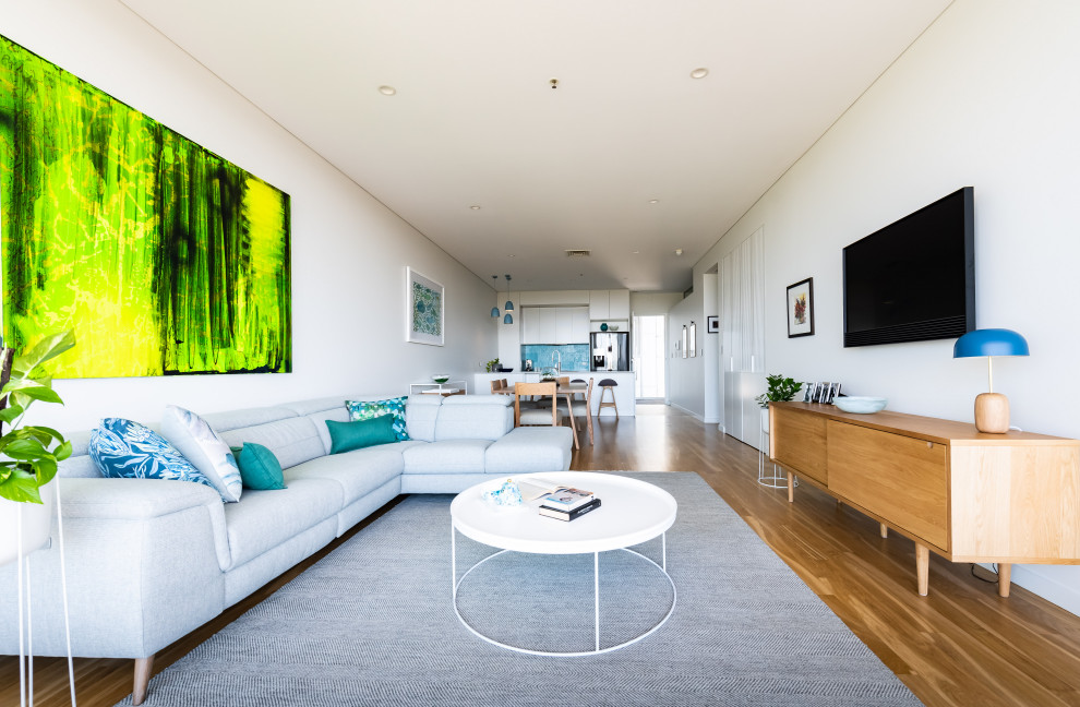 Kleines, Offenes Modernes Wohnzimmer mit weißer Wandfarbe, TV-Wand, braunem Holzboden und braunem Boden in Adelaide
