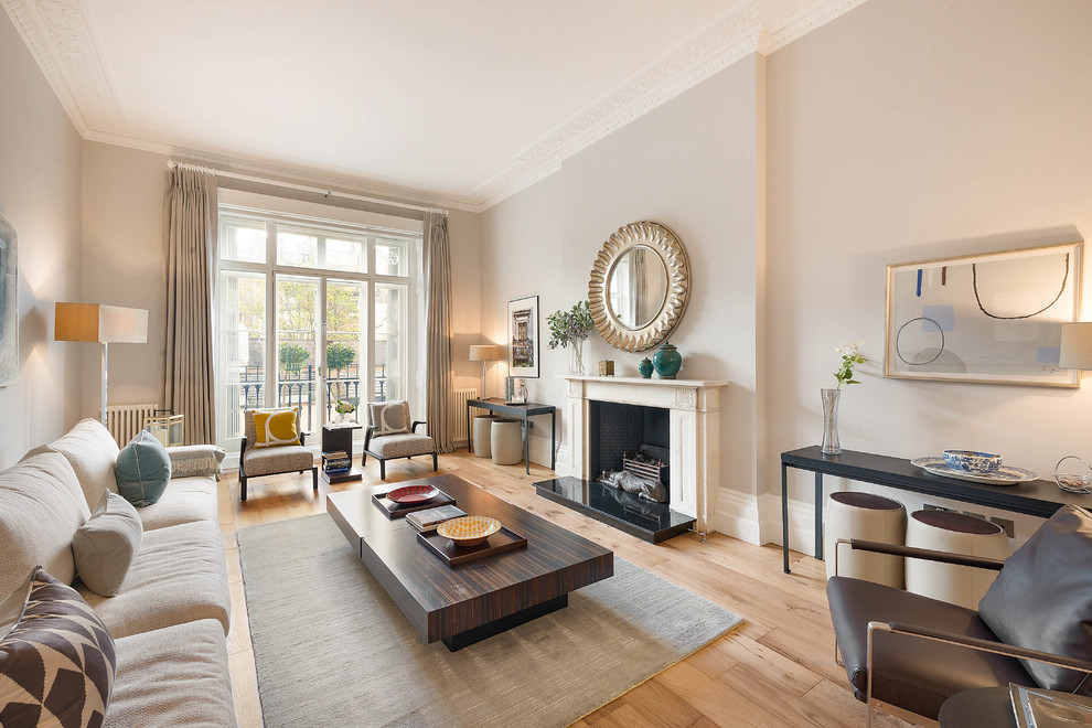 Photo of a classic formal living room in London with grey walls, light hardwood flooring, a standard fireplace, no tv and beige floors.