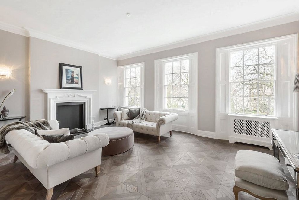 Medium sized traditional formal enclosed living room in London with grey walls, a standard fireplace, medium hardwood flooring, a stone fireplace surround and no tv.