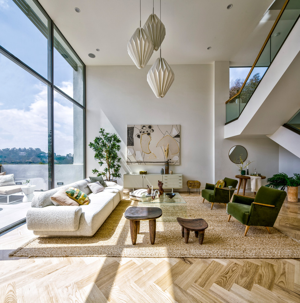 This is an example of a contemporary open plan living room in Los Angeles with white walls, light hardwood flooring and beige floors.