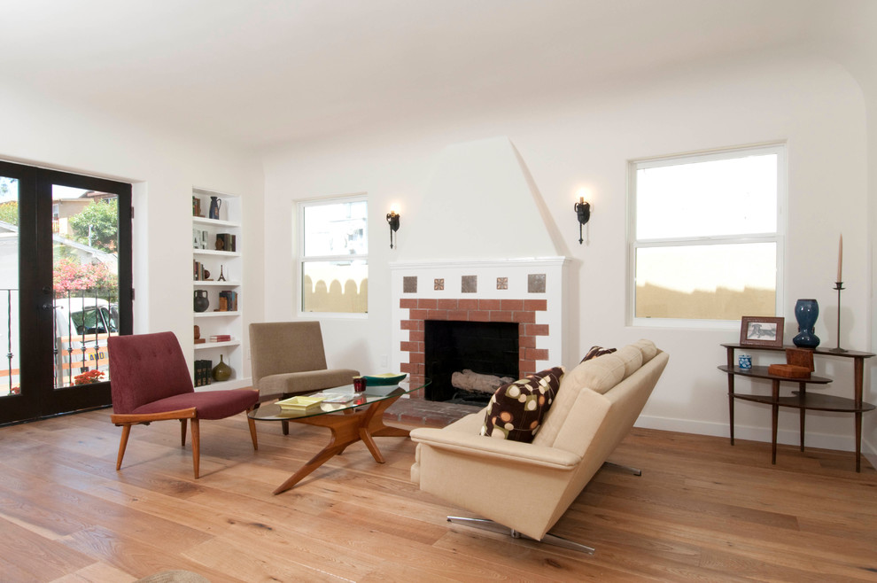 This is an example of a medium sized mediterranean formal open plan living room in Los Angeles with white walls, medium hardwood flooring, a standard fireplace and a brick fireplace surround.