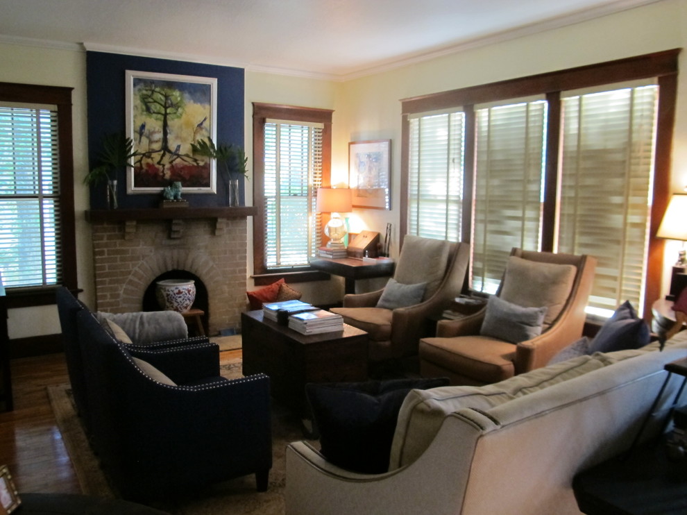 Exempel på ett mellanstort eklektiskt separat vardagsrum, med gula väggar, mellanmörkt trägolv, en standard öppen spis, en spiselkrans i tegelsten och en fristående TV