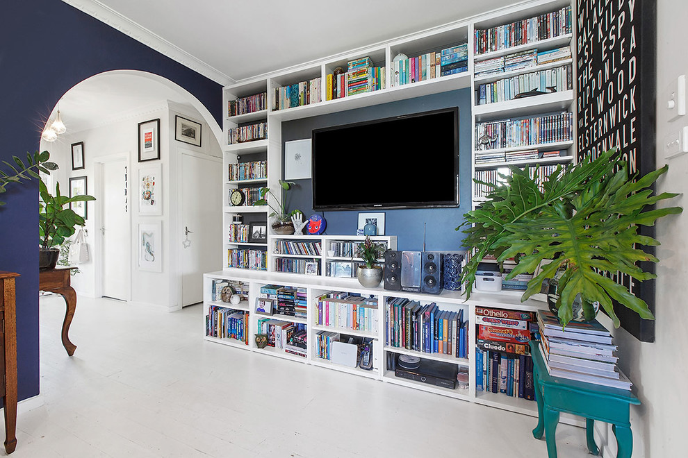 Ispirazione per un piccolo soggiorno bohémian aperto con libreria, pareti blu, parquet chiaro, TV a parete e pavimento bianco