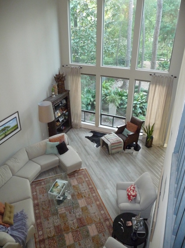 На фото: огромная гостиная комната в стиле фьюжн с белыми стенами, серым полом и красивыми шторами