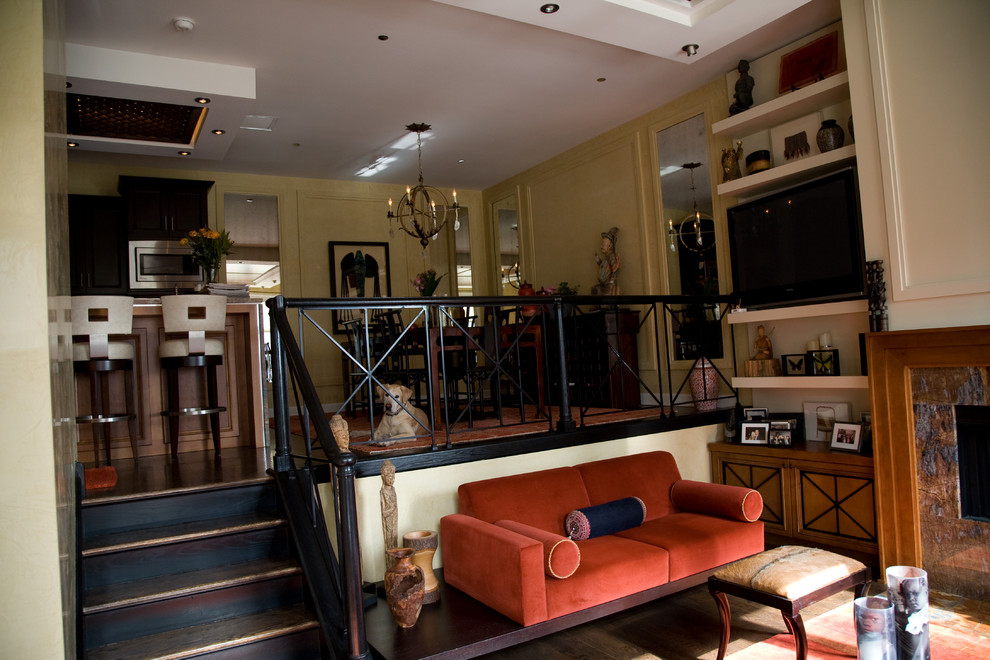 Пример оригинального дизайна: открытая гостиная комната среднего размера в стиле фьюжн с желтыми стенами, темным паркетным полом, стандартным камином, телевизором на стене, фасадом камина из камня и коричневым полом