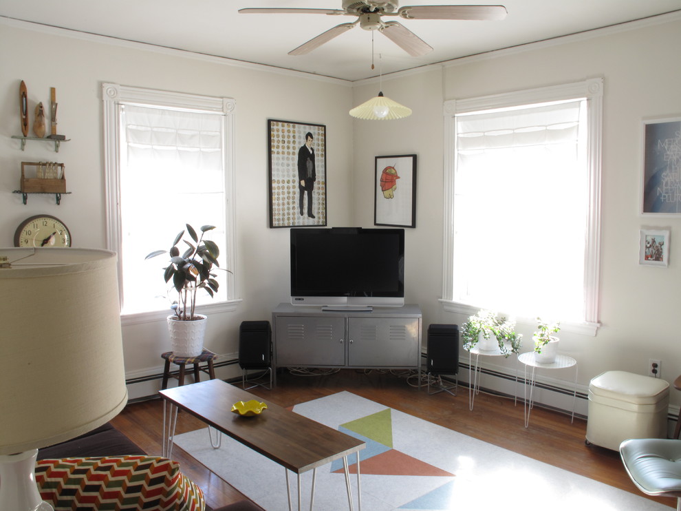 На фото: гостиная комната в стиле фьюжн с белыми стенами, паркетным полом среднего тона и отдельно стоящим телевизором с