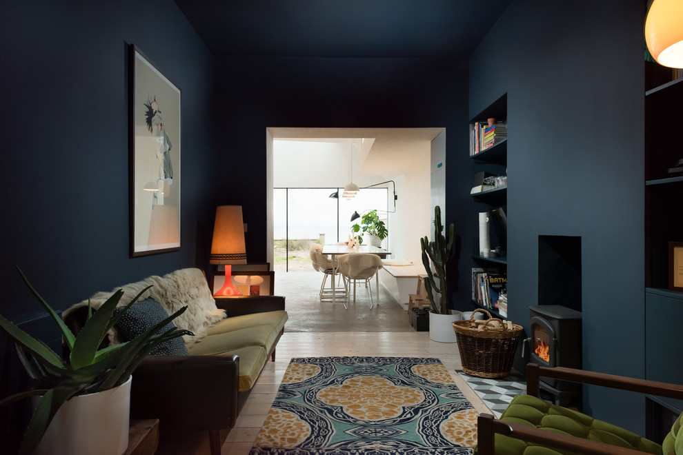 Réalisation d'un salon bohème de taille moyenne et ouvert avec un mur bleu, parquet clair, un poêle à bois, un manteau de cheminée en plâtre et éclairage.