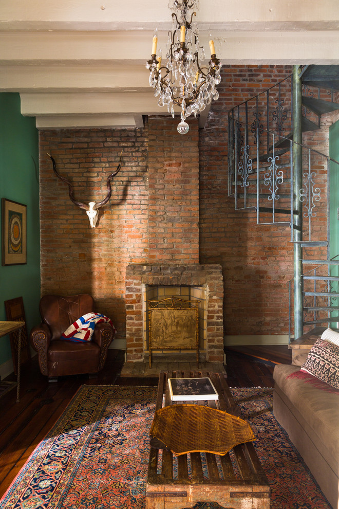 Cette image montre un salon bohème fermé avec une salle de réception, un mur vert, parquet foncé, une cheminée standard, un manteau de cheminée en brique et aucun téléviseur.