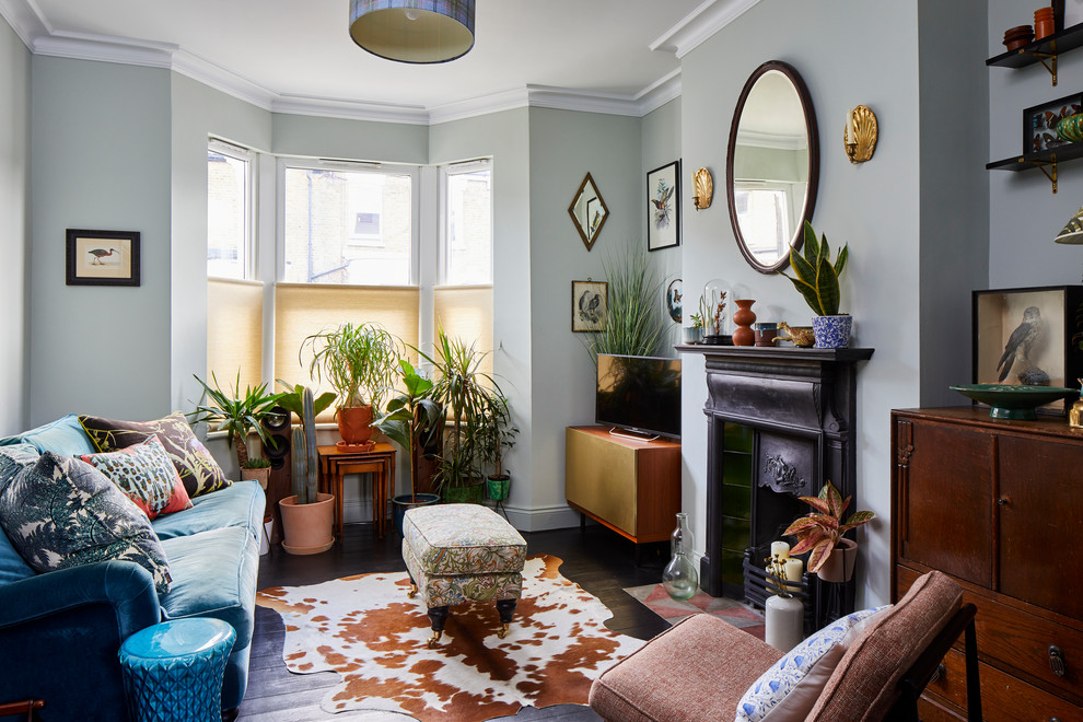 サリーにあるエクレクティックスタイルのおしゃれなリビング (グレーの壁、濃色無垢フローリング、標準型暖炉、青いソファ) の写真