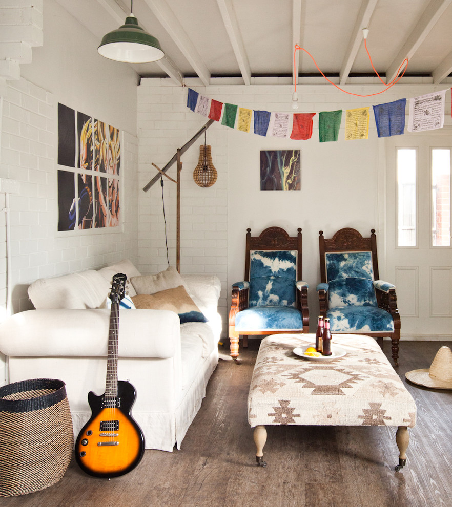 Imagen de salón bohemio con paredes blancas y suelo de madera en tonos medios