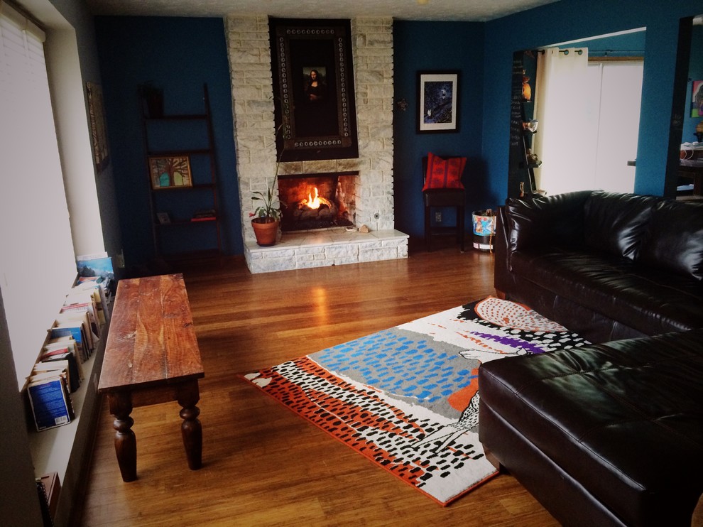 Immagine di un soggiorno bohémian di medie dimensioni e aperto con pareti blu, pavimento in bambù, camino classico, cornice del camino in pietra e nessuna TV