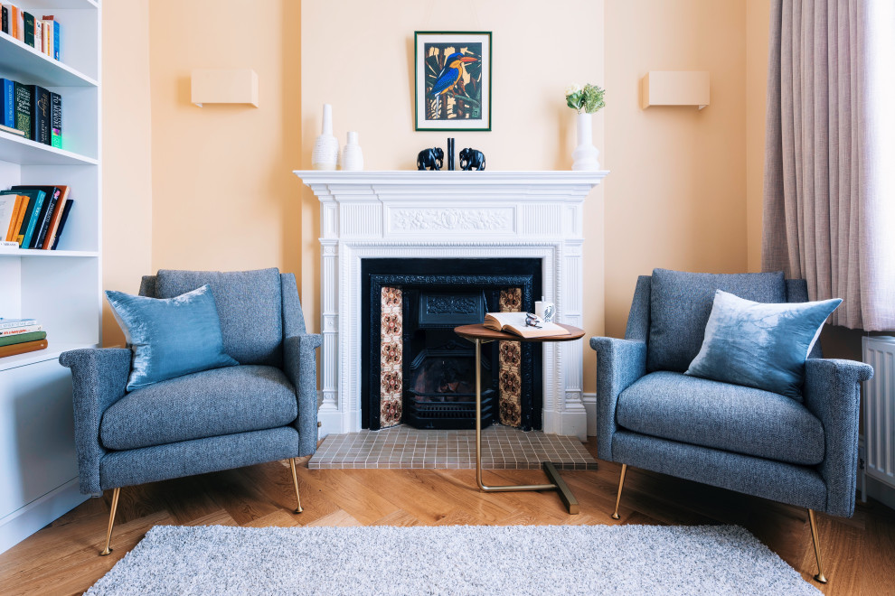 Aménagement d'un grand salon éclectique fermé avec un mur orange, un sol en bois brun, une cheminée standard, un manteau de cheminée en pierre, un téléviseur indépendant et un sol beige.