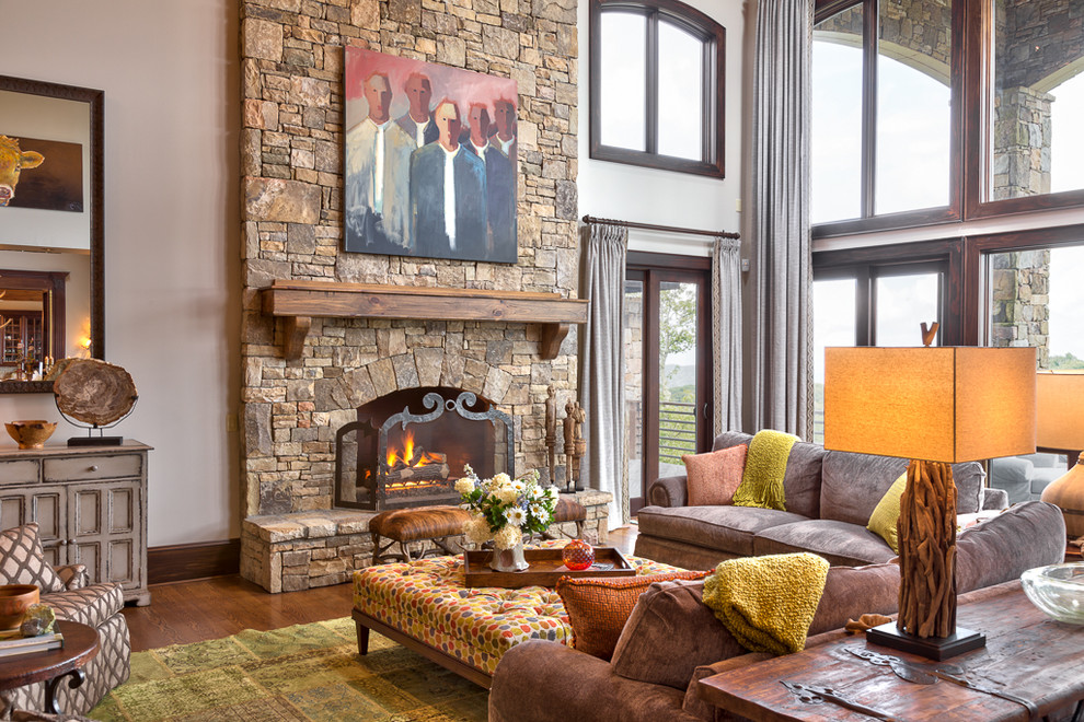 Inspiration for a mid-sized rustic open concept medium tone wood floor living room remodel in Charlotte with beige walls, a standard fireplace and a stone fireplace