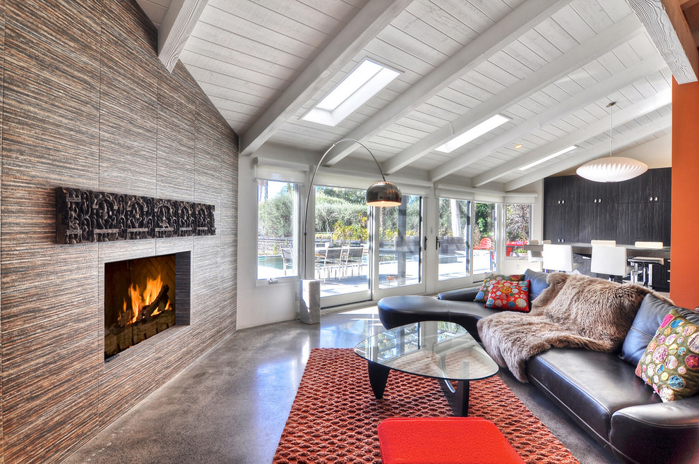 Design ideas for a retro open plan living room in Orange County with concrete flooring, white walls, a corner fireplace, a tiled fireplace surround and a wall mounted tv.