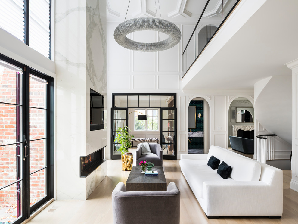 Diseño de salón abierto con paredes blancas, suelo de madera clara, chimenea lineal, televisor colgado en la pared y suelo beige