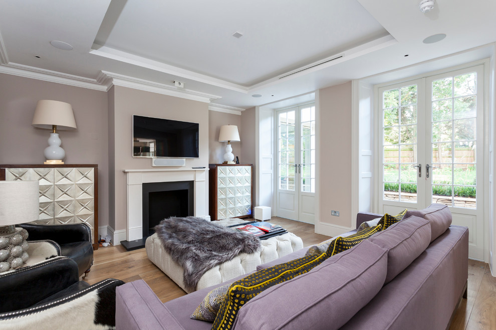 На фото: гостиная комната в стиле неоклассика (современная классика) с серыми стенами и телевизором на стене с