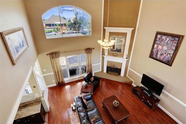 Foto de salón abierto extra grande con paredes beige, suelo de madera clara, chimenea de esquina, marco de chimenea de yeso y televisor independiente