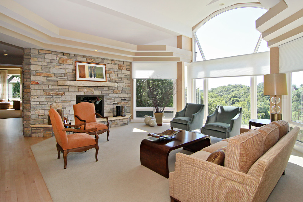 Traditional open plan living room in Minneapolis with a stone fireplace surround, beige walls and light hardwood flooring.