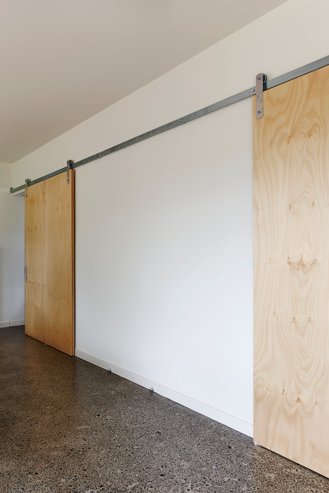 Diseño de salón abierto de tamaño medio con paredes blancas y suelo de cemento