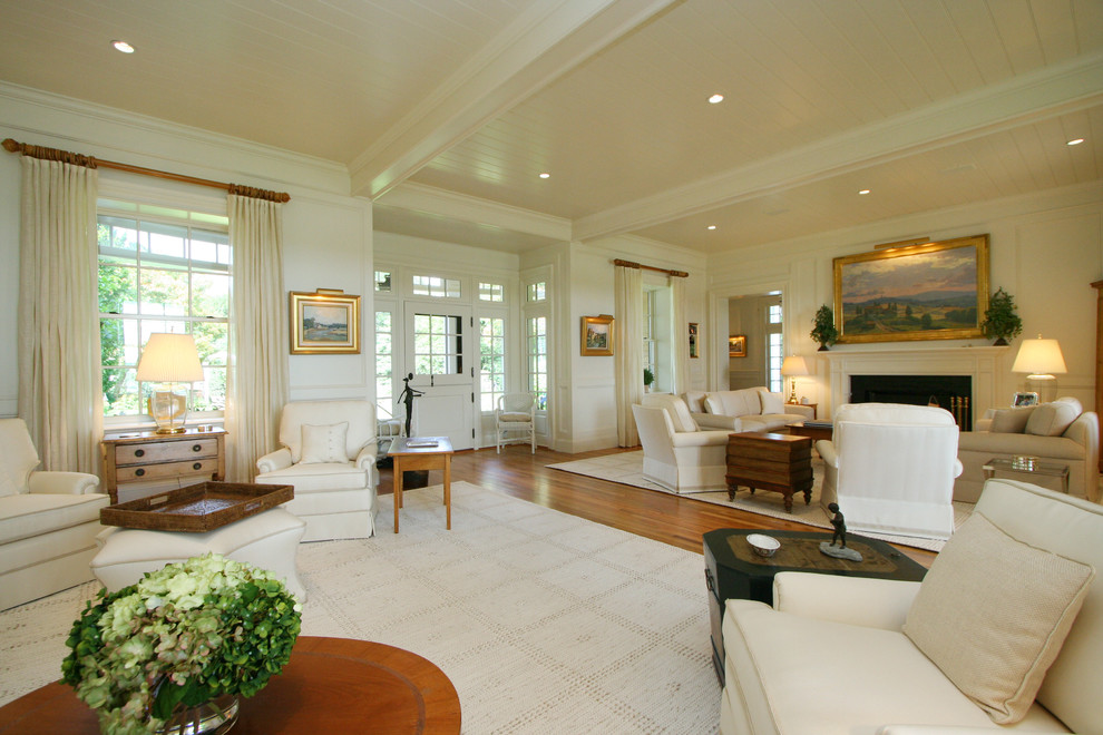 Cette image montre un grand salon marin ouvert avec une salle de réception, un mur blanc, un sol en bois brun, une cheminée standard et un manteau de cheminée en pierre.