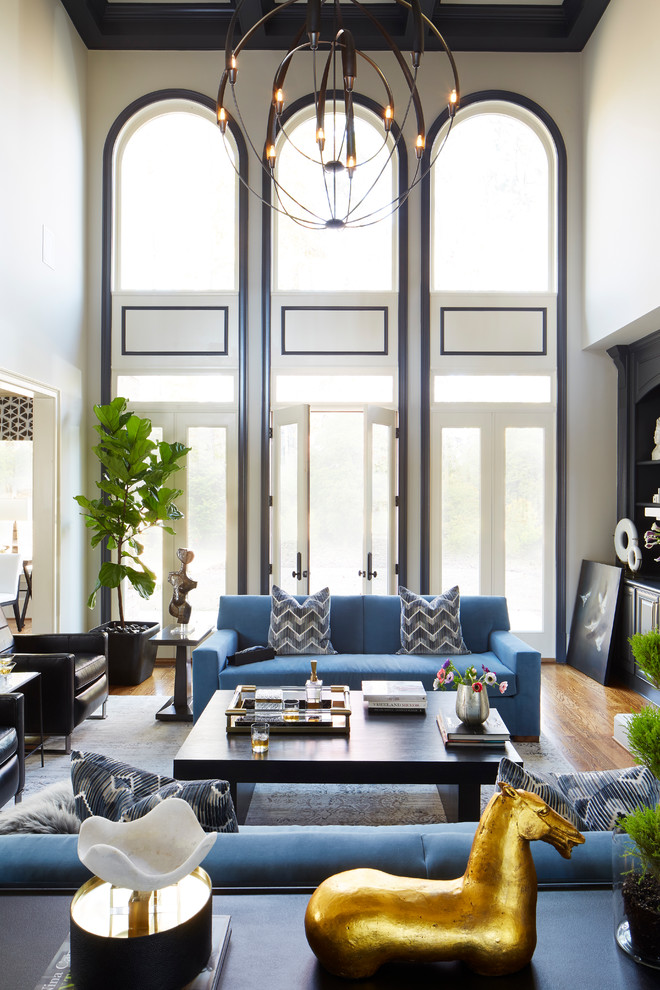 Идея дизайна: гостиная комната в стиле неоклассика (современная классика) с серыми стенами, паркетным полом среднего тона, стандартным камином, фасадом камина из камня, коричневым полом и синим диваном