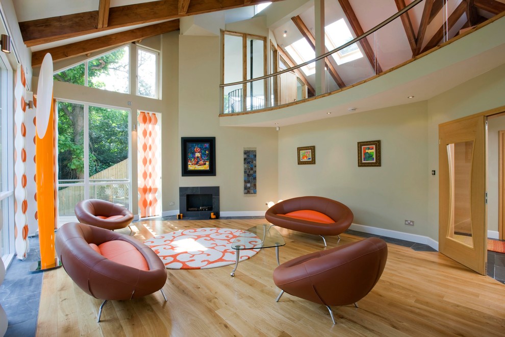Photo of a large contemporary open plan living room in Edinburgh with light hardwood flooring, a stone fireplace surround, no tv, beige walls and a standard fireplace.