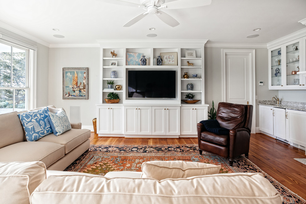 Foto de salón abierto de estilo americano de tamaño medio sin chimenea con paredes grises, suelo de madera en tonos medios y pared multimedia