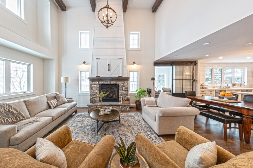 Example of a large arts and crafts formal and open concept vinyl floor, brown floor and exposed beam living room design in Edmonton with white walls, a standard fireplace, a stone fireplace and a media wall