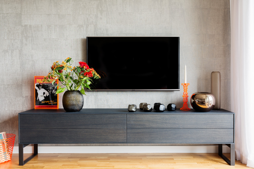 Foto di un grande soggiorno design aperto con pavimento in legno massello medio e TV a parete