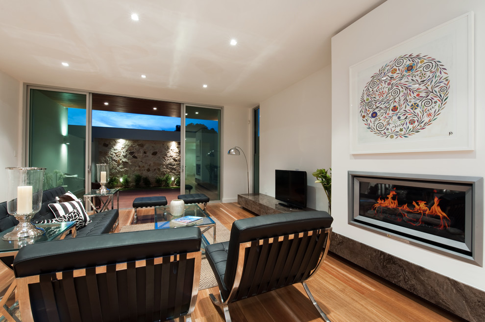 Medium sized contemporary open plan living room in Adelaide with white walls, medium hardwood flooring, a standard fireplace, a plastered fireplace surround and a freestanding tv.