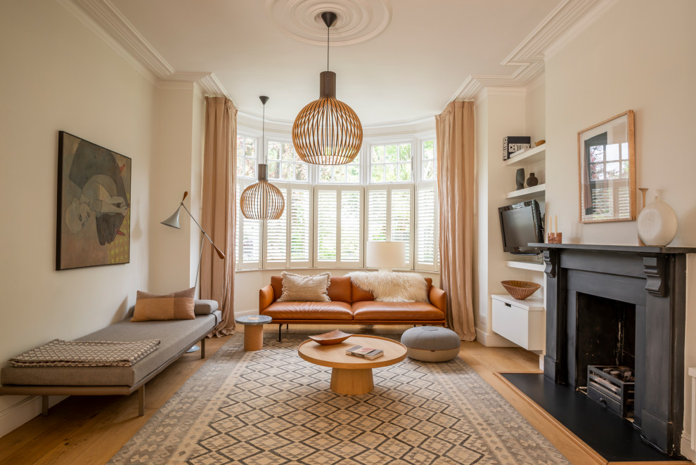 This is an example of a scandinavian living room in London with beige walls, light hardwood flooring, a standard fireplace and beige floors.