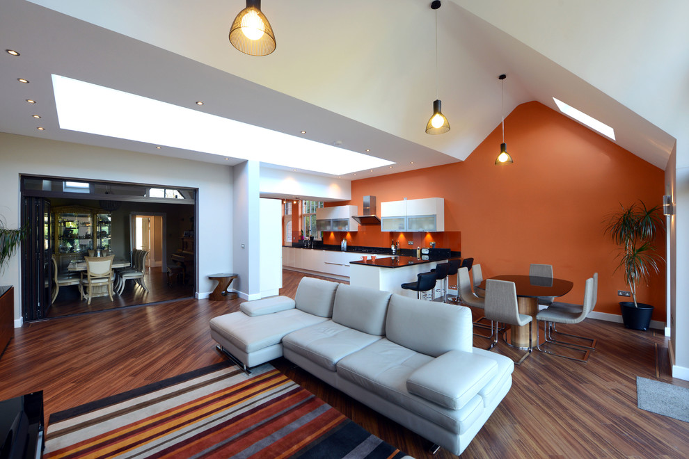На фото: огромная открытая гостиная комната в современном стиле с оранжевыми стенами и отдельно стоящим телевизором