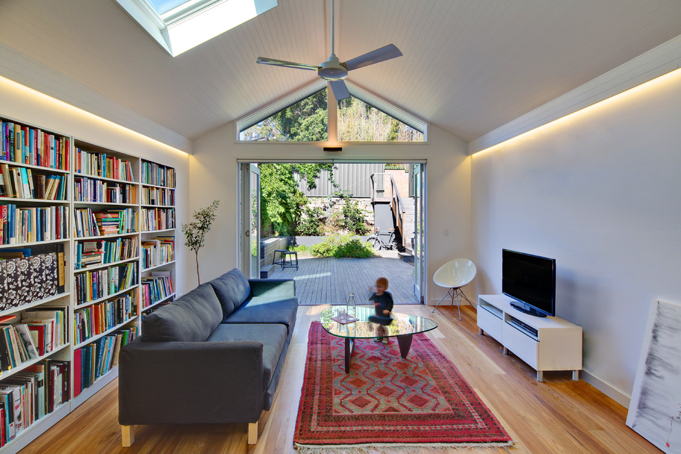Diseño de salón abierto contemporáneo de tamaño medio con paredes blancas, suelo de madera clara y televisor independiente