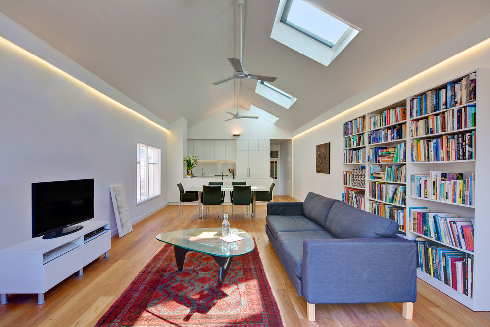 Источник вдохновения для домашнего уюта: открытая гостиная комната в современном стиле с белыми стенами, отдельно стоящим телевизором и синим диваном