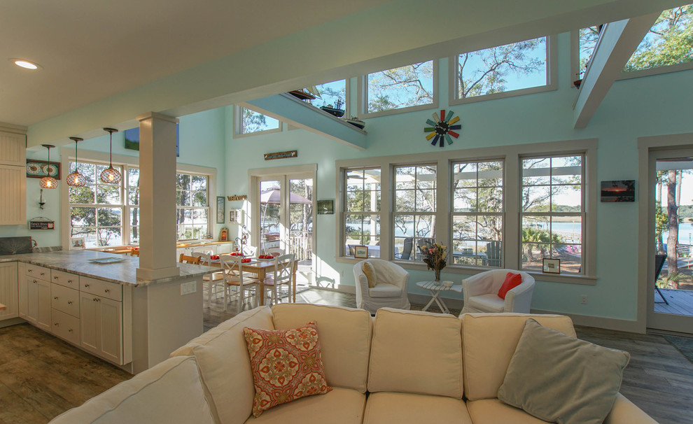 Großes, Offenes Maritimes Wohnzimmer ohne Kamin mit blauer Wandfarbe, braunem Holzboden und TV-Wand in Charleston