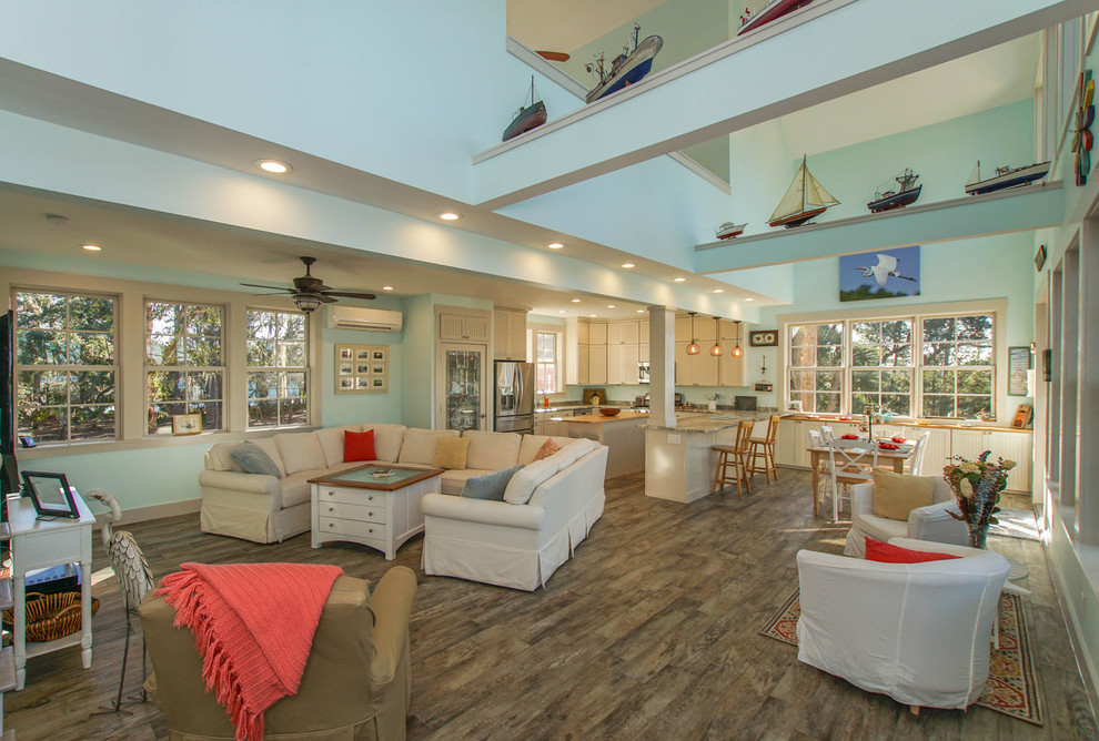 Foto de salón abierto costero grande sin chimenea con paredes azules, suelo de madera en tonos medios y televisor colgado en la pared