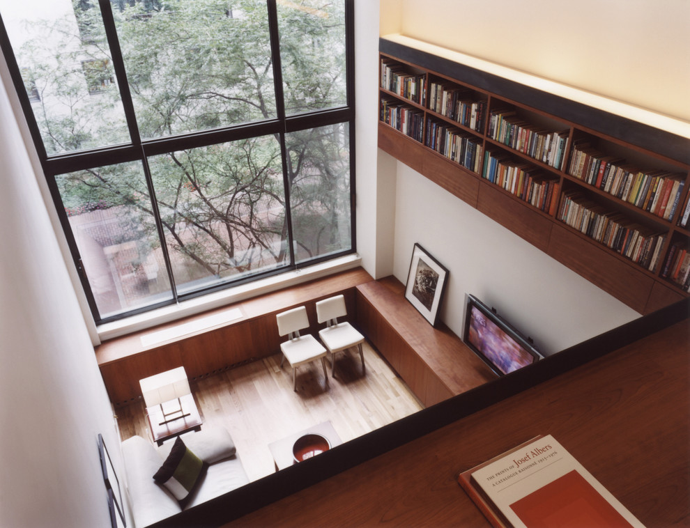 Inspiration pour un salon mansardé ou avec mezzanine minimaliste avec une bibliothèque ou un coin lecture, un mur blanc, parquet clair et un téléviseur fixé au mur.