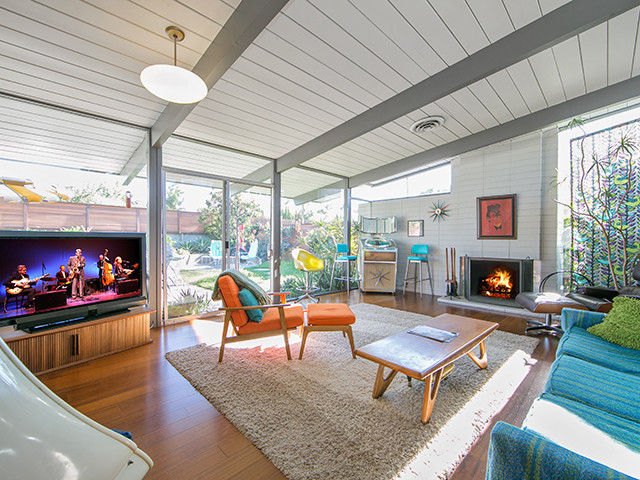 Inspiration for a medium sized retro open plan living room in Orange County with white walls, medium hardwood flooring, a standard fireplace, a brick fireplace surround and a freestanding tv.