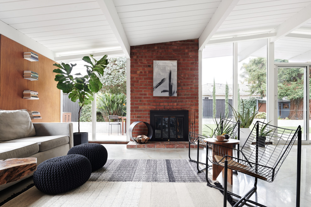 Example of a mid-century modern open concept concrete floor, gray floor, shiplap ceiling, vaulted ceiling and wood wall living room design in San Francisco with brown walls, a standard fireplace and a brick fireplace