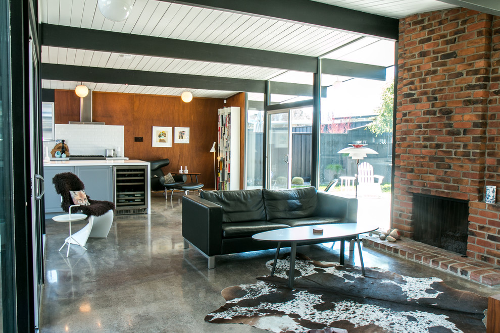 Пример оригинального дизайна: открытая гостиная комната среднего размера в стиле ретро с коричневыми стенами, бетонным полом, стандартным камином и фасадом камина из кирпича