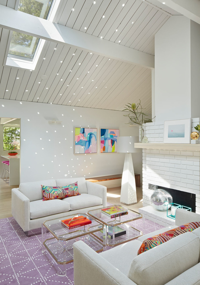 Esempio di un soggiorno minimalista con sala formale, pareti bianche, pavimento in legno massello medio, camino classico e cornice del camino in mattoni