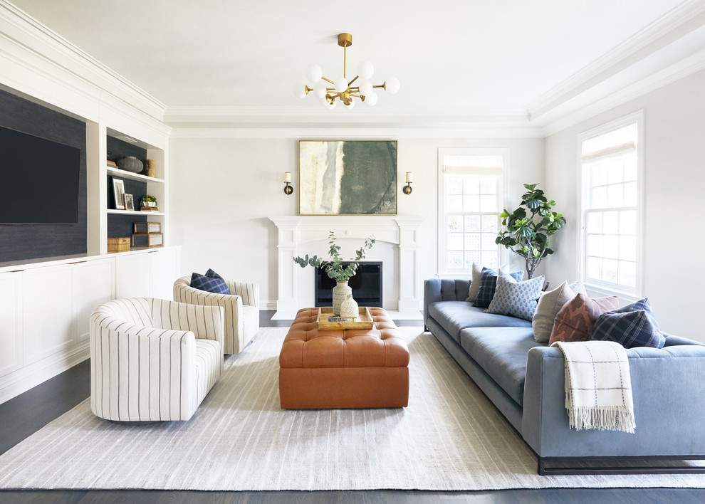 Свежая идея для дизайна: гостиная комната в стиле неоклассика (современная классика) с белыми стенами, темным паркетным полом, стандартным камином, телевизором на стене, серым полом и синим диваном - отличное фото интерьера