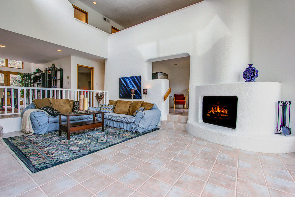 Photo of an expansive contemporary formal open plan living room in Albuquerque with white walls, ceramic flooring, a corner fireplace, a plastered fireplace surround and a concealed tv.
