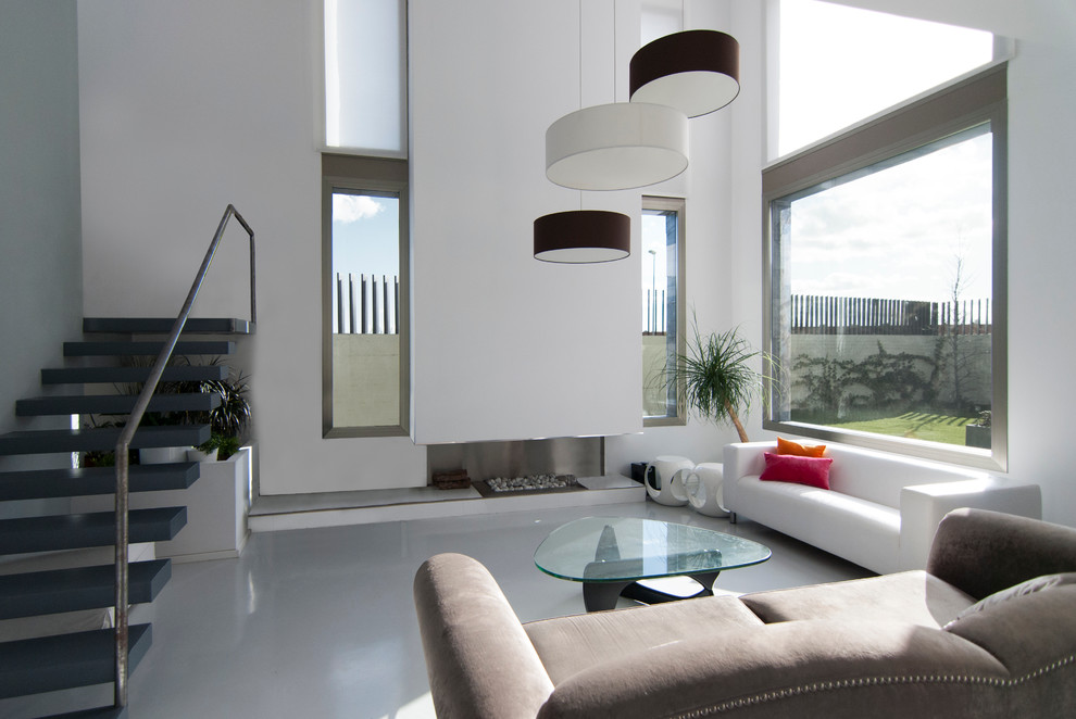 Exempel på ett modernt allrum med öppen planlösning, med ett finrum, vita väggar, betonggolv, en bred öppen spis, en spiselkrans i metall och en fristående TV