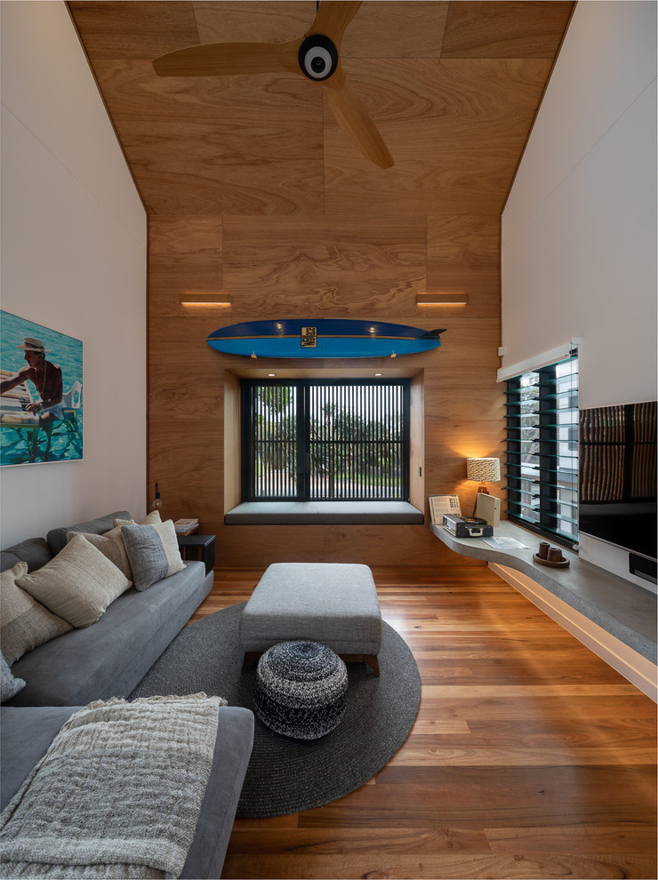 Foto di un soggiorno costiero con pareti bianche, pavimento in legno massello medio, TV a parete e pavimento marrone