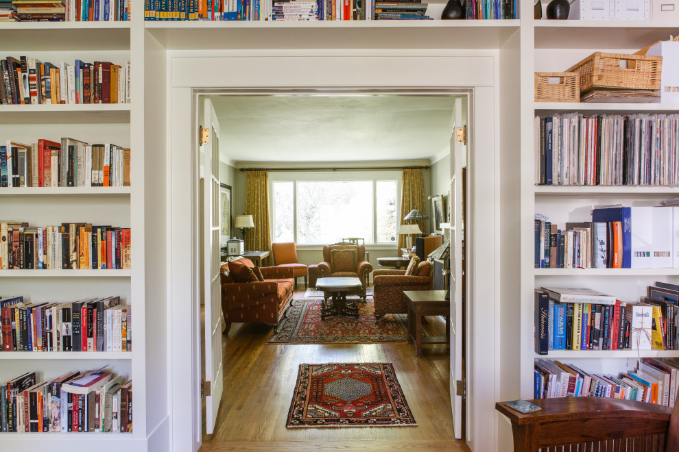 Cette photo montre un salon craftsman de taille moyenne et fermé avec une bibliothèque ou un coin lecture, un mur vert, un sol en bois brun et un sol marron.