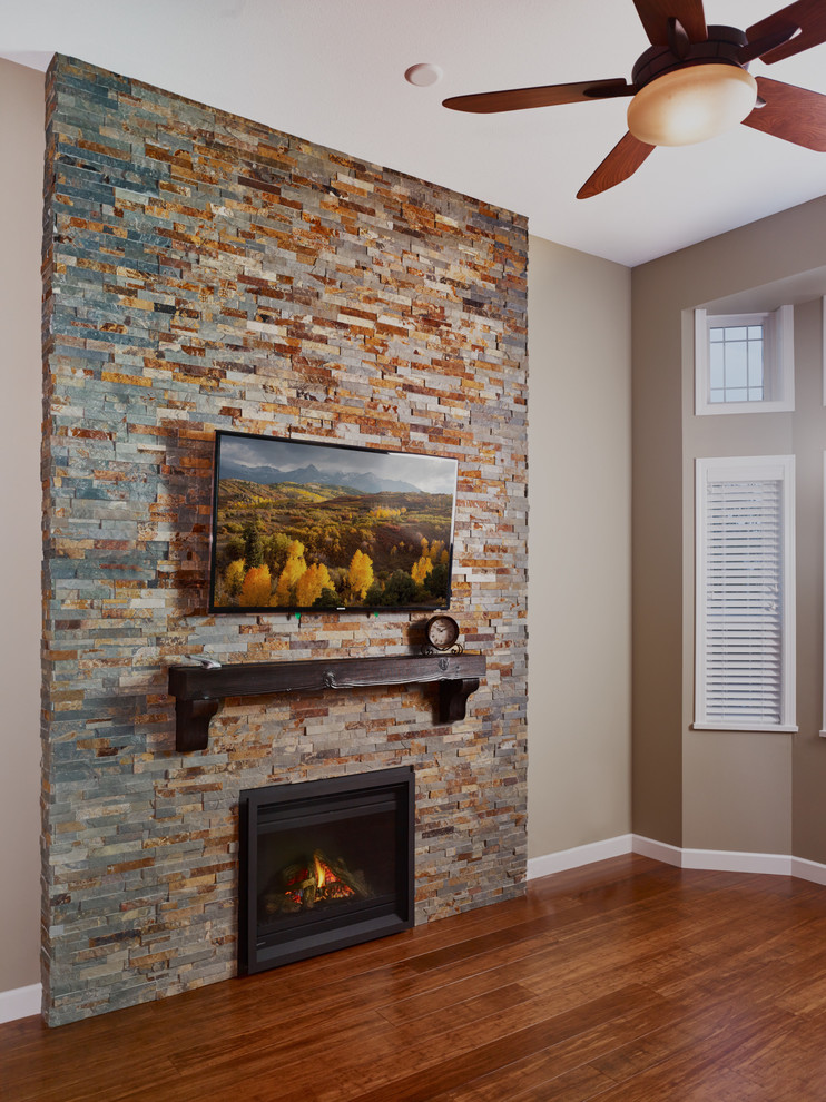 バンクーバーにあるお手頃価格の中くらいなトランジショナルスタイルのおしゃれなリビング (緑の壁、竹フローリング、標準型暖炉、石材の暖炉まわり、壁掛け型テレビ、茶色い床) の写真