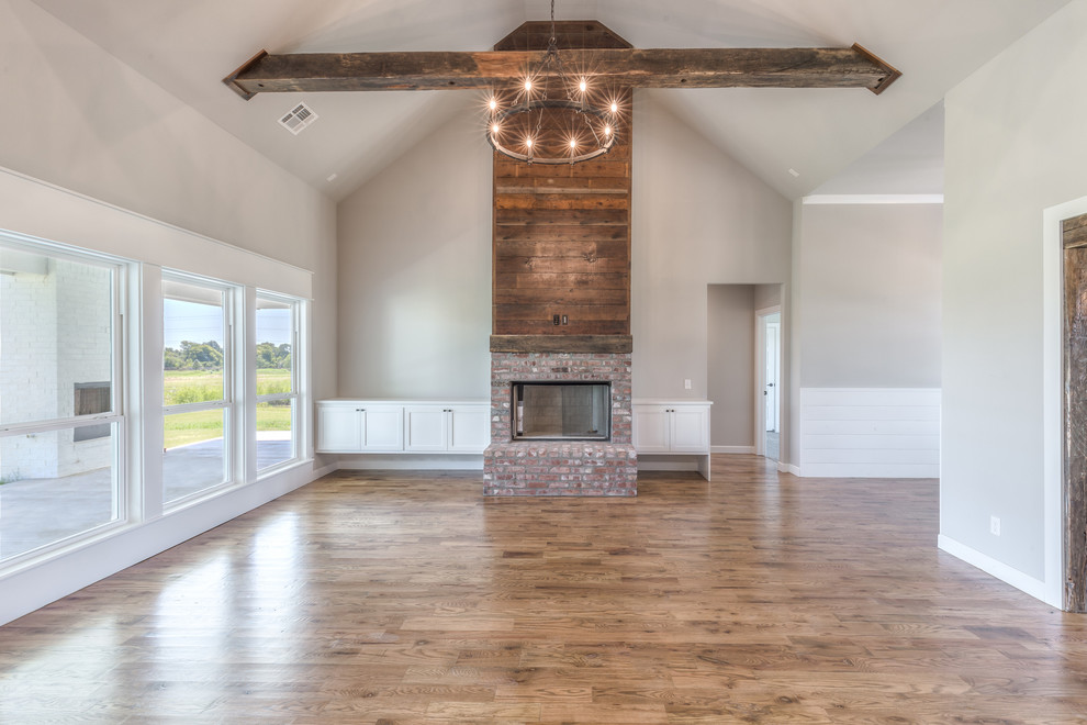 Inspiration for a large cottage formal and open concept medium tone wood floor and brown floor living room remodel in Other with gray walls, a standard fireplace, a brick fireplace and no tv