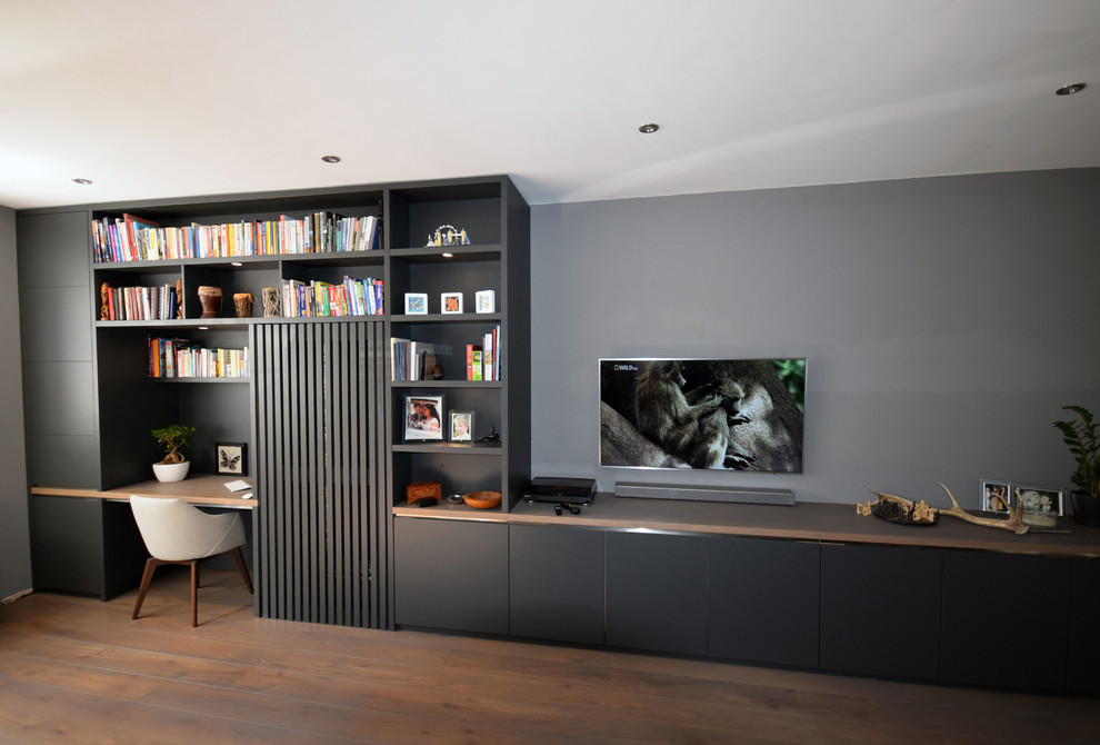 Immagine di un grande soggiorno moderno con pareti grigie, parquet chiaro, nessun camino e TV a parete